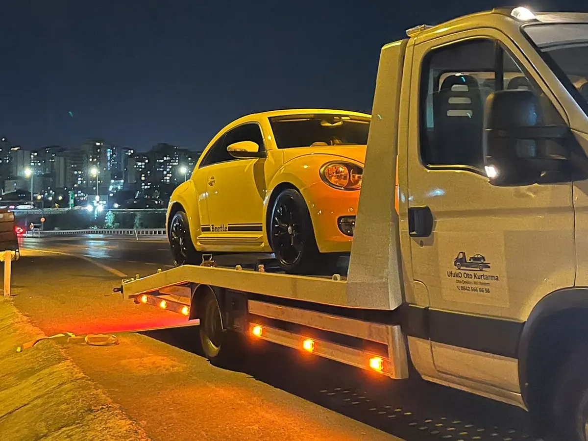 Gece kayar kasa çekici üzerinde taşınan sarı hatchback araç