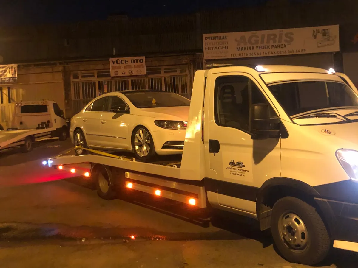 Gece çekici platformuna yüklenmiş beyaz sedan araç