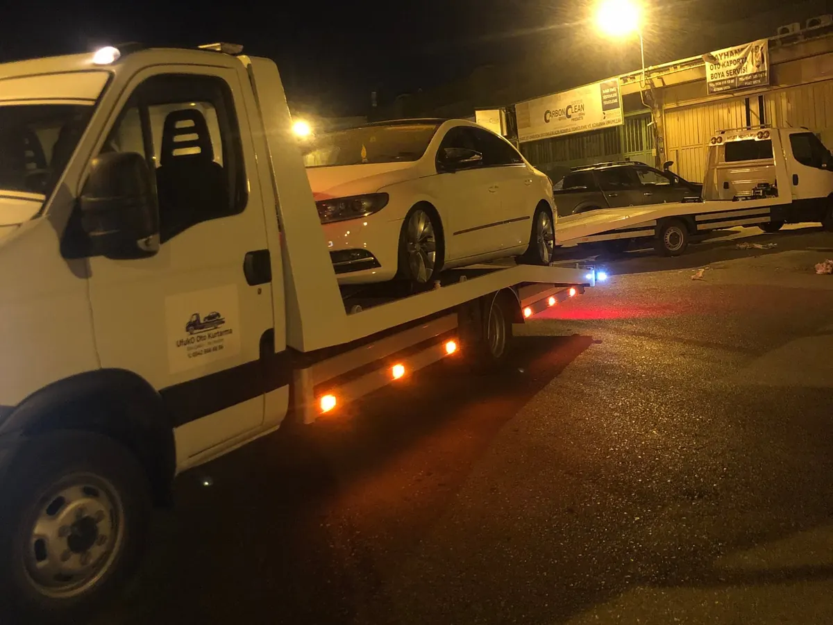 Gece sokak lambası altında çekiciye yüklenmiş beyaz sedan