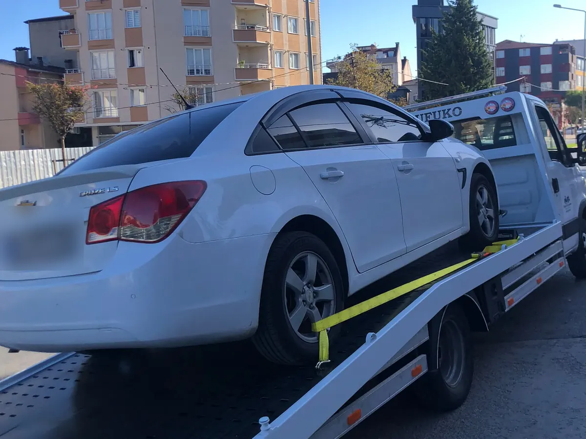 Beyaz sedan aracın çekici platformunda kayışla sabitlenmesi
